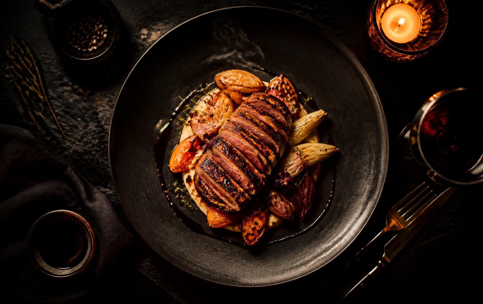 Chef-plated main course under warm candlelight